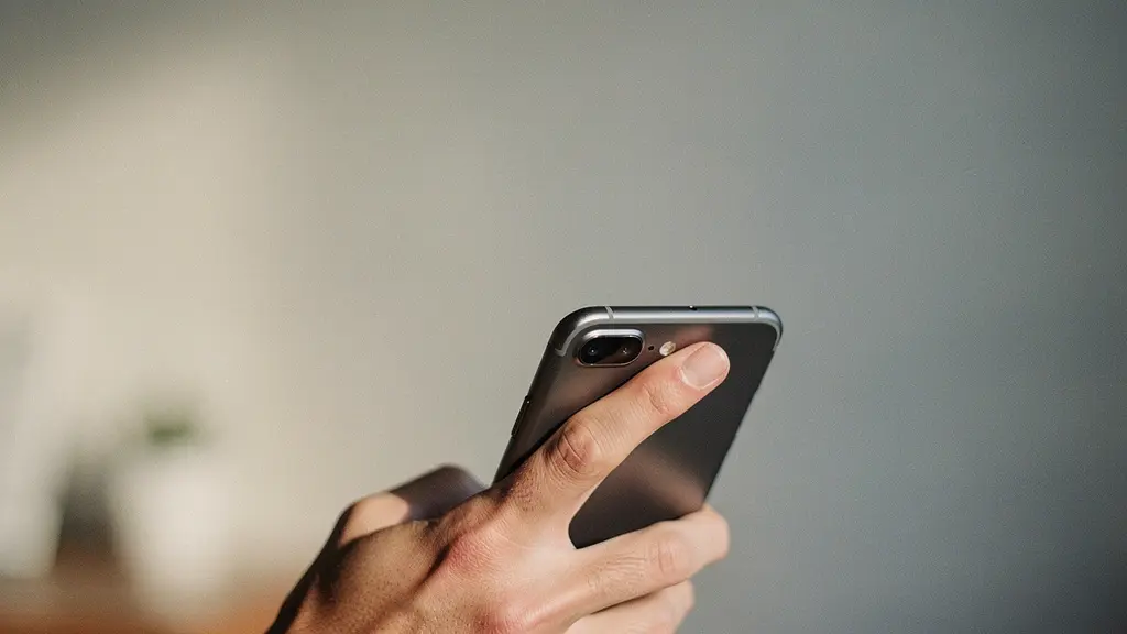 Main tenant un smartphone de dos, le pouce étiré vers le haut comme pour atteindre un menu, avec un large espace vide au-dessus suggérant une zone difficile d'accès.